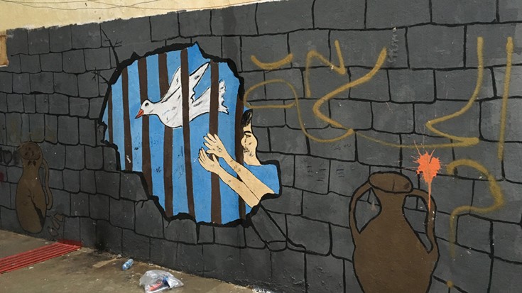 Προσφυγόπουλα γεμίζουν χρώμα τους τοίχους μιας φυλακής